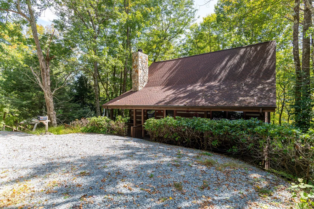 This exterior image captures the cabin’s wooden exterior, a prominent stone chimney, and lush greenery surrounding the property. The porch and accessible natural setting evoke a sense of connection to the great outdoors, perfect for pet owners seeking adventure with their dogs.