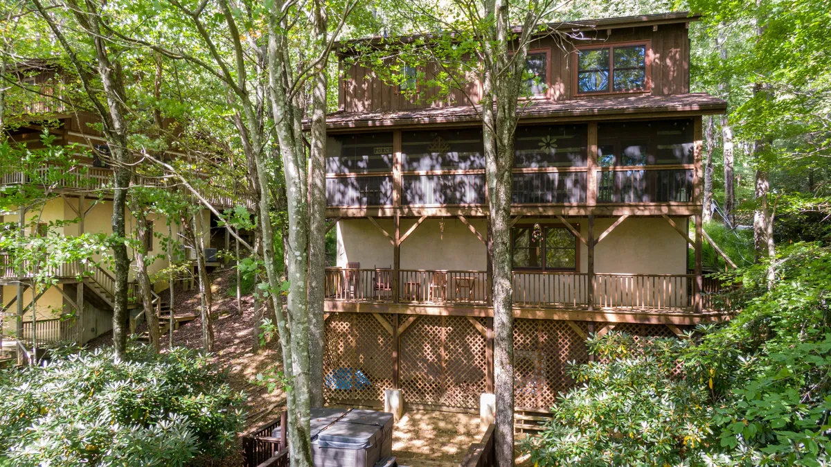 This photo showcases wooden balconies and a deck area surrounded by trees, creating an immersive nature experience. The setting highlights outdoor relaxation spots where both guests and their dogs can unwind after a day on the trails.