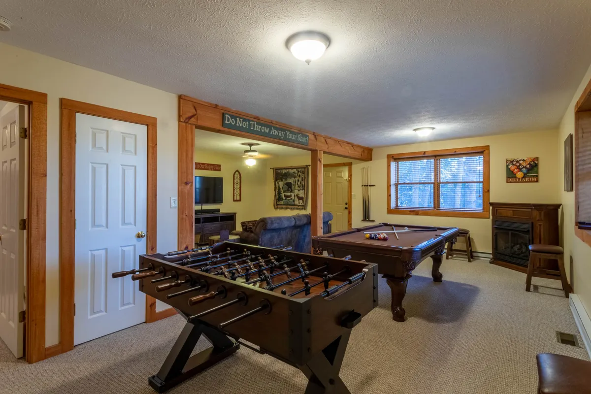 A spacious loft area featuring a foosball table and pool table, complemented by comfortable seating and decorative wall art. Natural light pours in, creating a lively yet cozy atmosphere perfect for leisure and socializing.