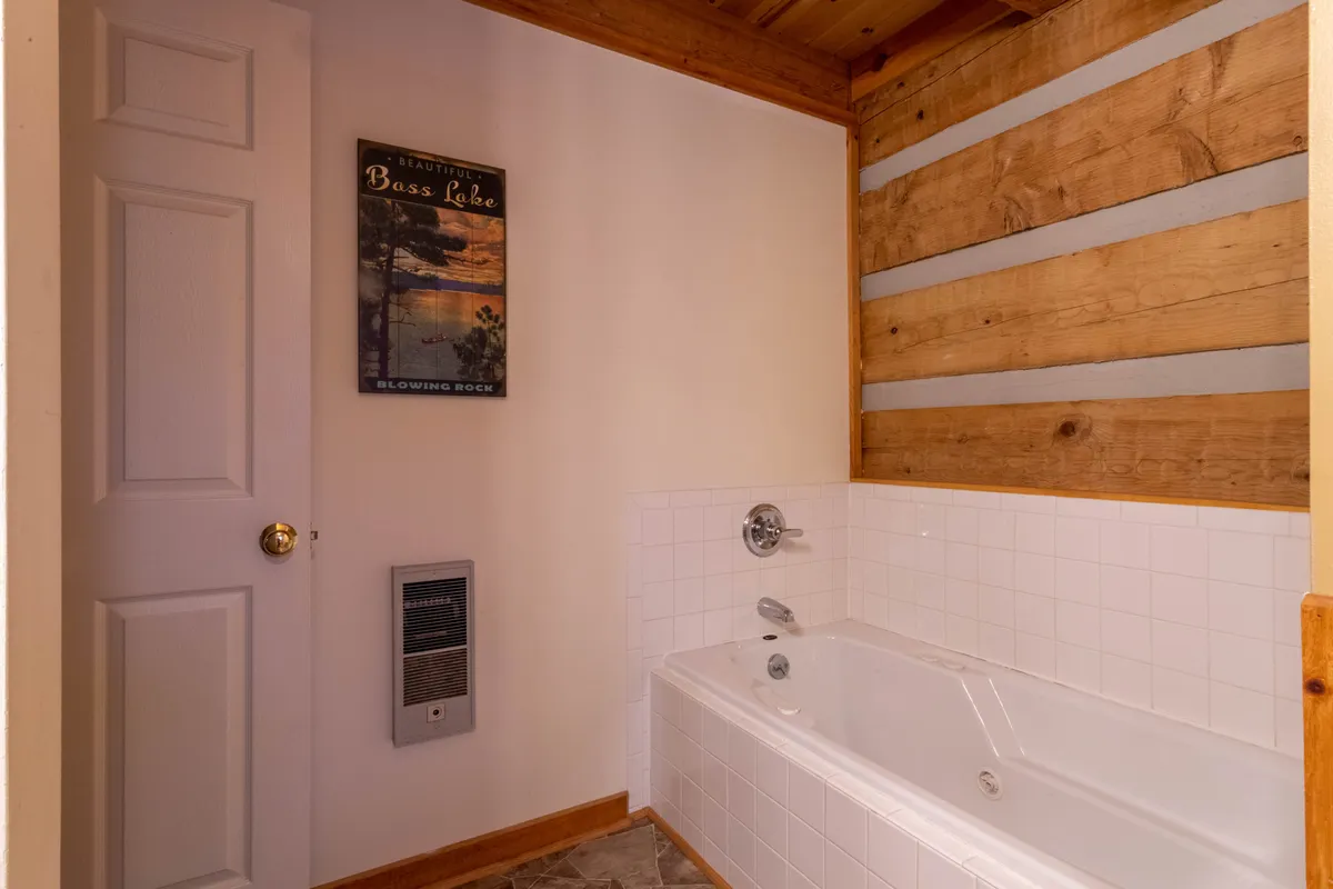 This interior image highlights a jacuzzi tub, wooden accent wall, and a Bass Lake poster, creating a spa-like, tranquil atmosphere. The setup invokes the idea of relaxation and rejuvenation, perfect for soaking tired muscles after mountain adventures.